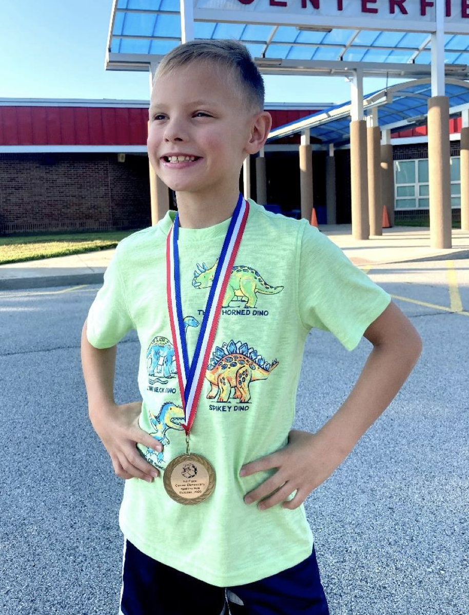 A picture of a kid proudly displaying an athletic and academic metal from presentation solutions recognizer machine